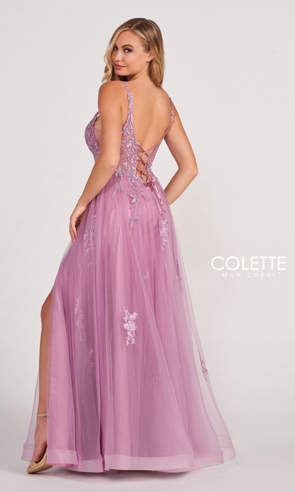 A woman poses with one hand on her hip in the CL2074 Tulle A-Line Prom Dress with a sheer bodice, low back, side slit, and lavender lace appliques.